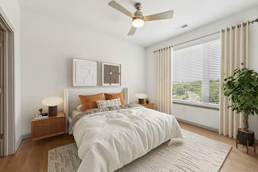 A bedroom with a large bed, a ceiling fan, and a potted plant at The Waterford At Rocketts Landing Apartments, PRG Real Estate, Richmond, Virginia