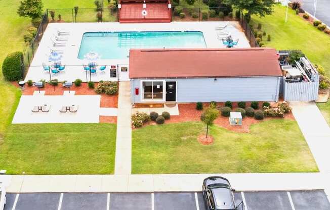 A car is parked in a parking lot in front of a building with a pool.