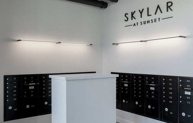 A white reception desk with a black control panel and a sign at Skylar At Sunset Apartments, California