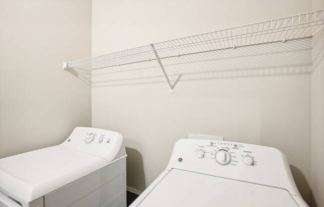 a washer and dryer in a laundry room with a rack on the wall