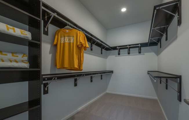 a walk in closet with a yellow shirt hanging on the wall and a black closet  at The Clearing at ONE28, Olathe, Kansas