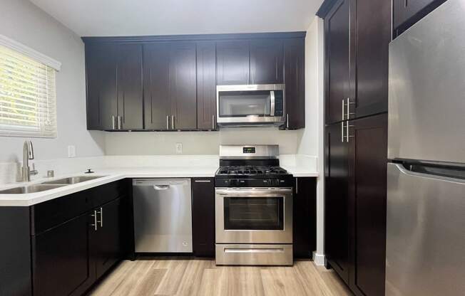 an empty kitchen with stainless steel appliances and black cabinets