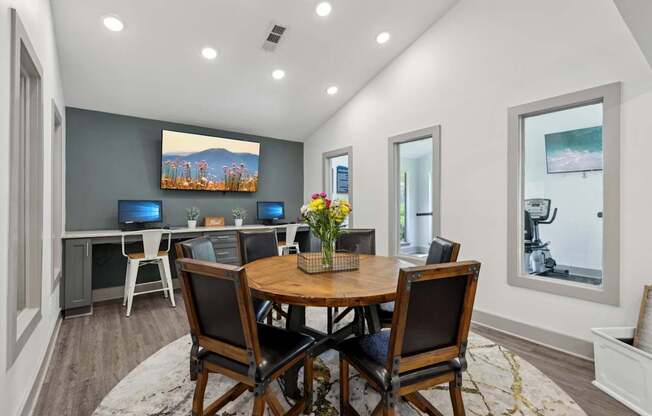 A business center with a wooden table and chairs and computers at Gwinnett Square Apartments in Duluth, GA