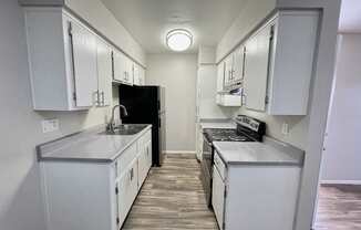 A kitchen with white cabinets and a black refrigerator.