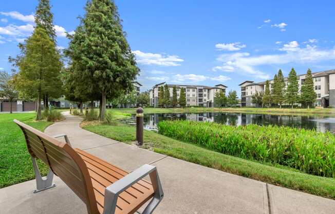a park bench overlooking a lake with apartment buildings in the background