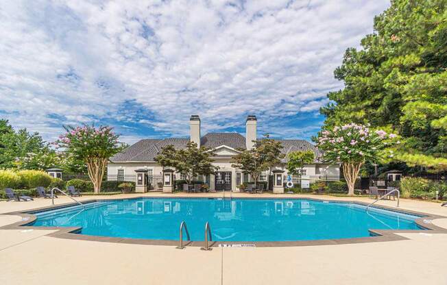 A large swimming pool in front of a house with a pool house.