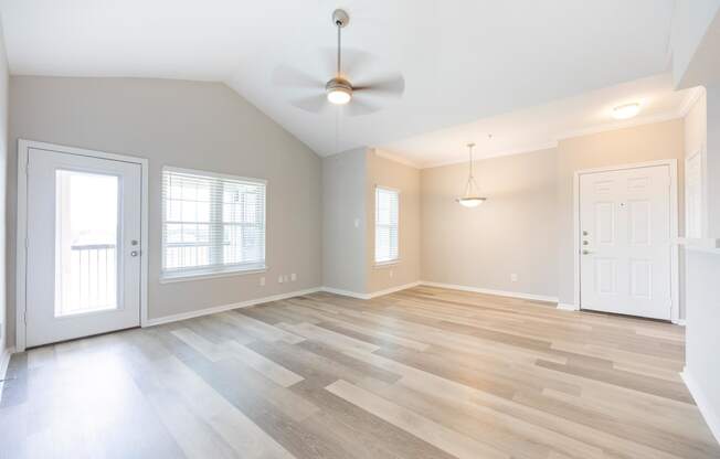 an empty living room with wood floors and a ceiling fan