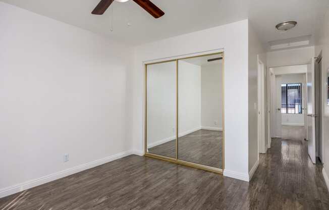 an empty room with a ceiling fan and a mirrored closet