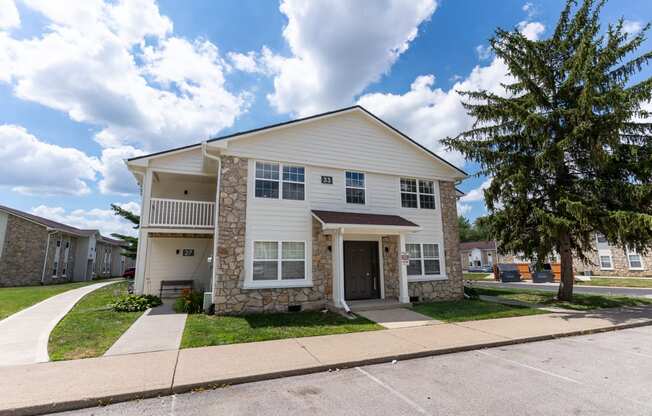 a white and stone house with a sidewalk in front of it