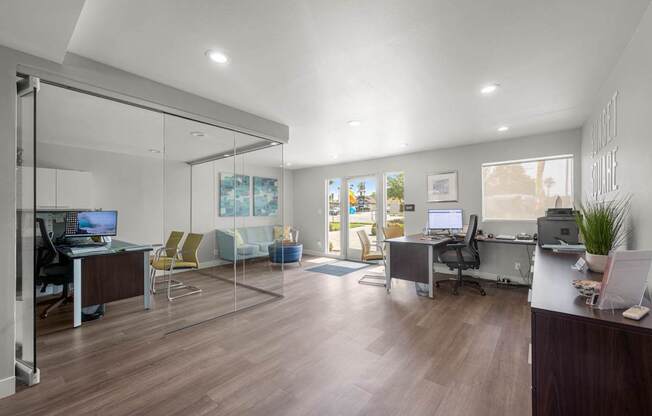 A modern office with glass walls and wooden floors.