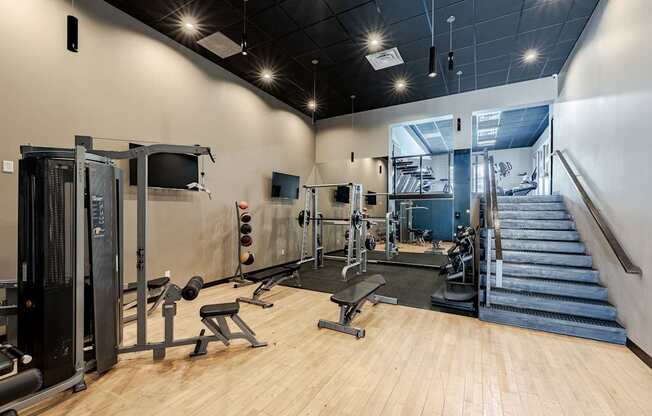 A gym with a variety of equipment including a treadmill, weights, and a bench press.