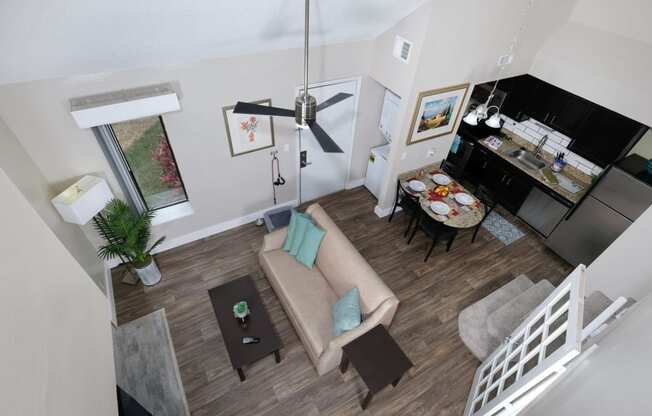 View of Fusion Orlando apartment living space from loft. Open concept living room and kitchen with ceiling fan and in unit laundry.
