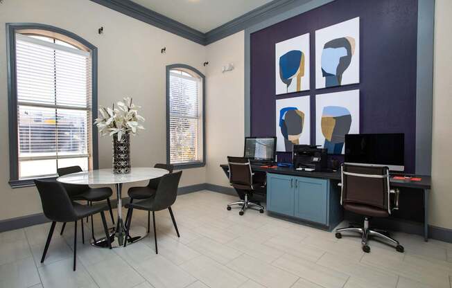 A room with a table, chairs, and computers.