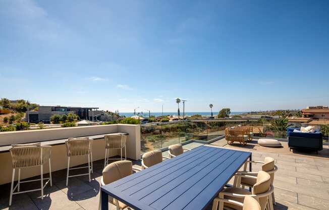 a rooftop patio with a blue table and chairs and a view of the ocean