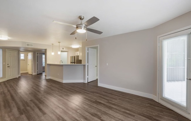 Step into our inviting living room adorned with sleek hardwood floors and complemented by a gentle ceiling fan breeze at Boulders at Lookout Mountain Apartment Homes, Phoenix, 85022