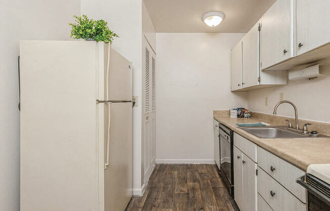 a small kitchen with white cabinets and a refrigerator