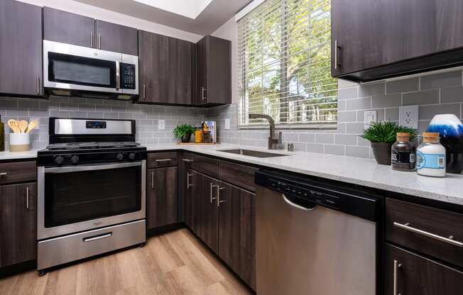 Spring Valley, NV, 89147 Apartments - Alicante - Kitchen with Hardwood-Style Floor, Quartz Countertops, Stainless-Steel Appliances, and Wooden Cabinets