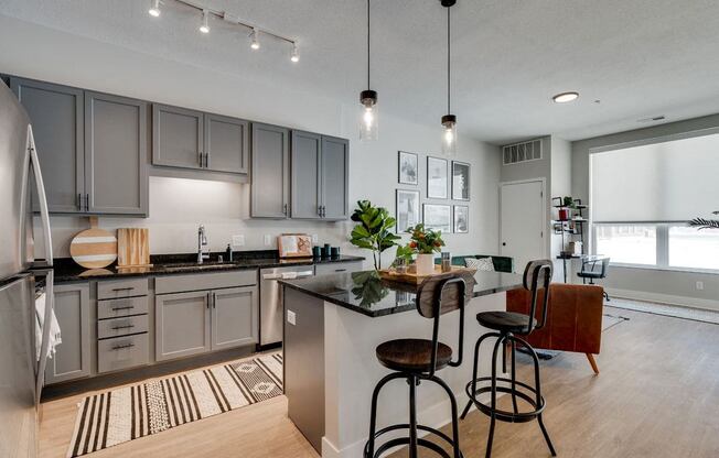 an open kitchen and living room with a bar and stools