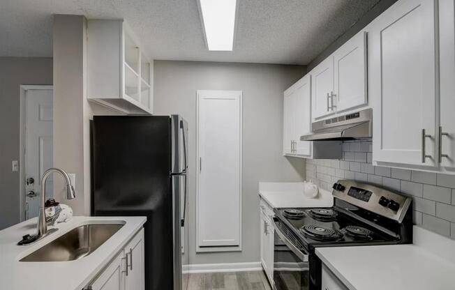 a kitchen with white cabinets and black appliances at The Sapphire, Decatur, Georgia