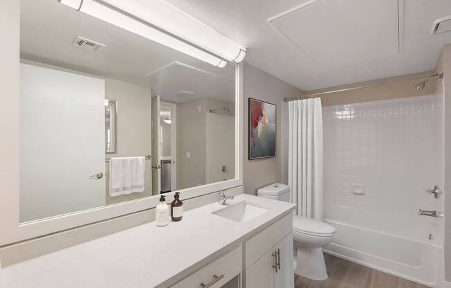 A white bathroom with a toilet, sink, and mirror.