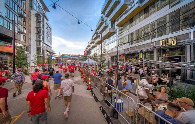 A busy street scene with people walking and sitting at outdoor tables.