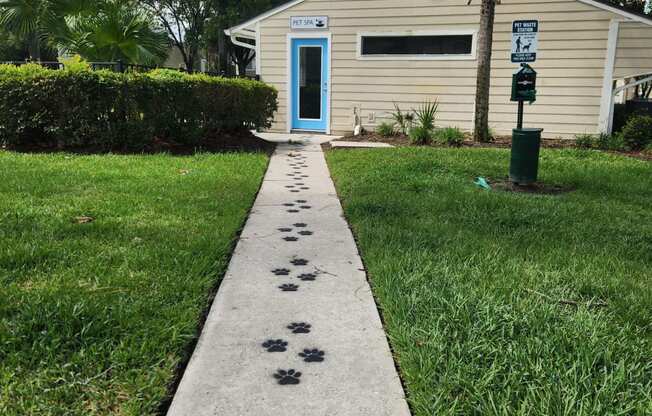 a walkway leading to a house with paw prints on the sidewalk