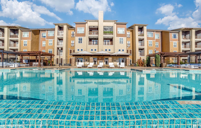 a swimming pool with an apartment building in the background