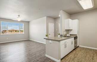 an empty kitchen and living room with white cabinets and a window