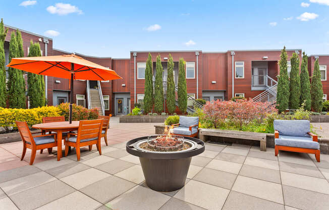 A patio with a fire pit and chairs.