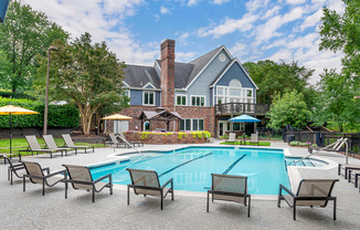 a swimming pool with chairs and a house in the background