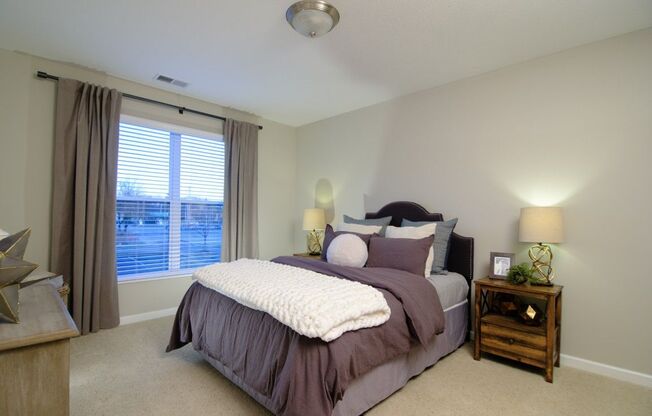 A bedroom with a bed, nightstand, and window.