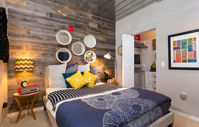 a bedroom with a bed with blue and yellow pillows and a reclaimed wood wall at Ann Arbor City Club, Ann Arbor Michigan