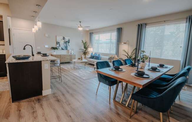 A modern kitchen with a dining table set for six open to the living space.