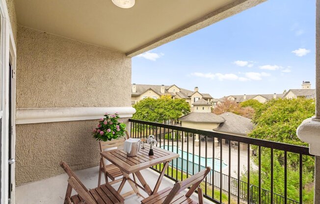 a balcony with a table and chairs and a pool in the background