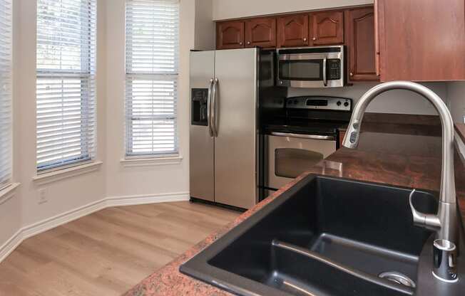 A kitchen with a black sink and stainless steel appliances.