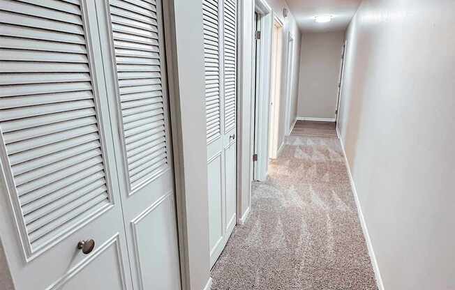 A long hallway with white doors and carpeted floors.