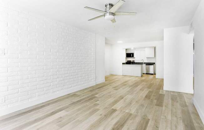 A room with a ceiling fan and wooden flooring.