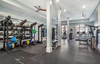 A gym with a variety of equipment including weight plates, weightlifting equipment, and a bench press.