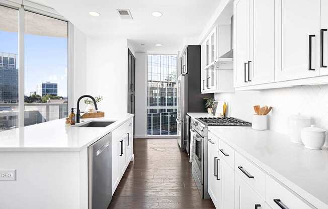 A modern kitchen with white cabinets and a view of the city.