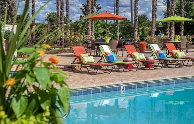 a swimming pool with lawn chairs and umbrellas next to a pool