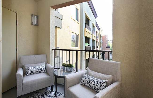 A balcony with two chairs and a table. at The Kitt at Warner Center Apartments, Woodland Hills, CA