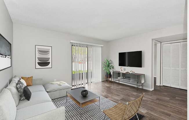 Model Living Room with Wood-Style Flooring and Patio Accessibility at Grand Pavilion Apartments in Tampa, FL.