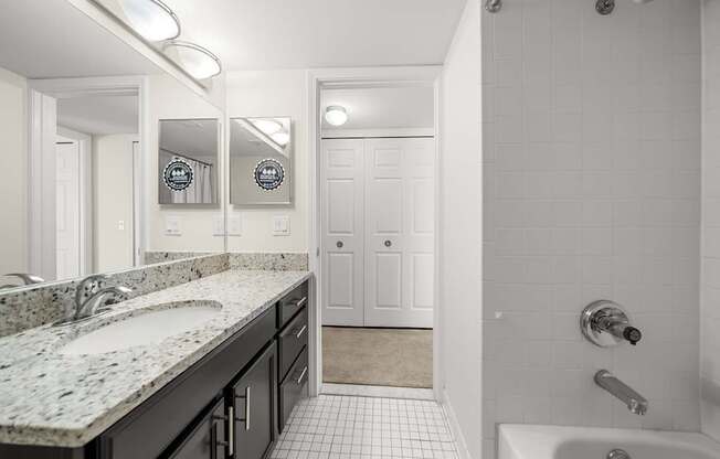Modern bathroom with large vanity mirror and tub/shower at Lakeside Village Apartments in Clinton Township, MI