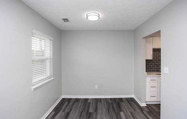 A room with a window and a wooden floor.