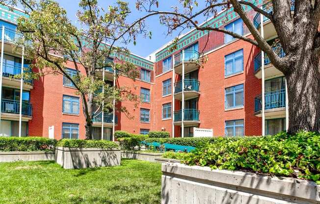 an exterior view of an apartment building with a lawn and trees