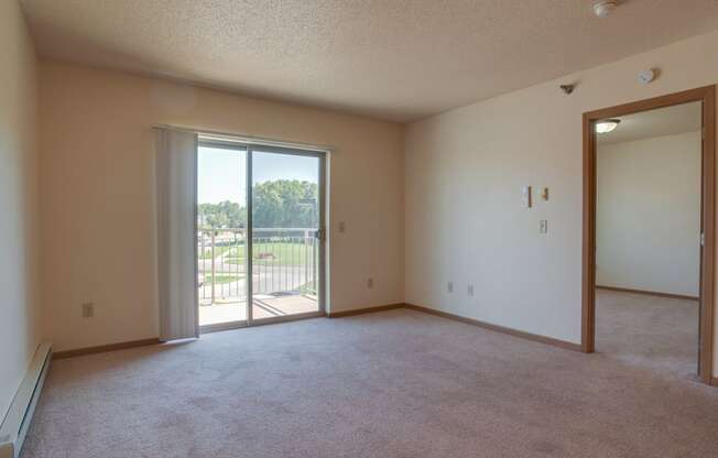 A room with a carpeted floor, a sliding glass door, and a mirror on the wall.