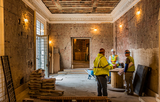 During Renovation: Skilled construction team discussing plans in a room with exposed brick