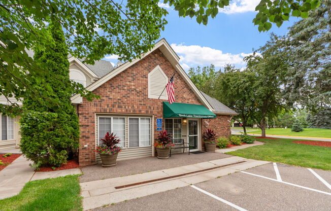 A small brick building with a green awning and an American flag on the front.