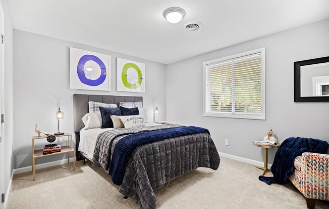 A bedroom with a bed, a chair, and a mirror.