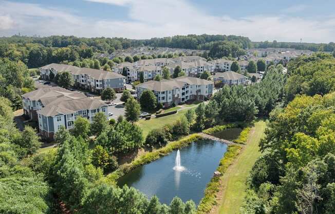 A bird's eye view of a residential area with a pond and greenery.